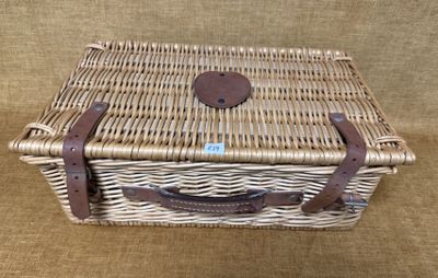 un panier de pique-nique en osier avec des anses en cuir, sur fond marron