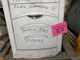 un réfrigérateur blanc posé sur une palette, à côté d'un tas d'autres objets