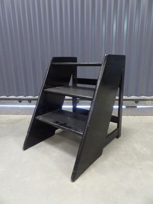 an image of a black step stool in front of a metal wall