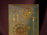 a gold clock with gears and a pendulum on a table