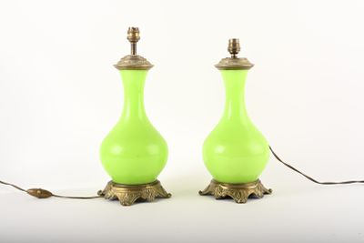 une paire de lampes en verre vert avec des pieds en laiton, posées sur une surface blanche