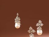 a pair of pearl and diamond earrings on a brown background