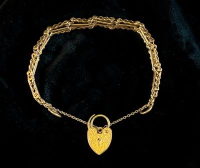 a gold bracelet with a heart shaped lock on it