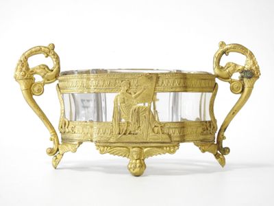 a gold vase with a glass in it on a white surface