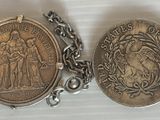 deux pièces d'argent sont posées sur une chaîne, sur une surface blanche