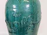 a green vase that is sitting on a white surface