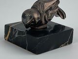 statue représentant un poisson posée sur un socle en marbre, sur fond blanc
