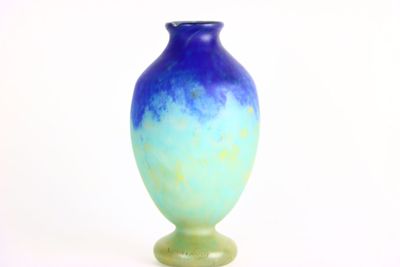 un vase bleu et vert posé sur une surface blanche