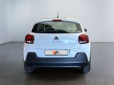 the rear end of a small white car in a white room
