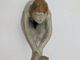 a small figurine of a man sitting on a white surface