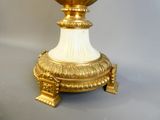 un vase doré et blanc posé sur un socle, sur une surface grise