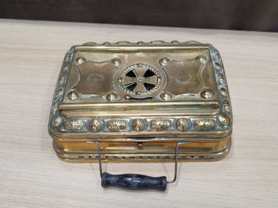 une petite boîte en métal posée sur une table, munie d'une poignée