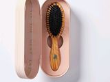 a wooden brush in a pink case on a white surface