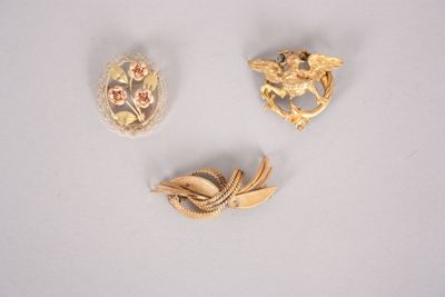 three gold brooches and a broochle on a white surface