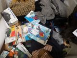 a pile of books on a bed next to a purse