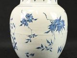 a white vase with blue flowers on it on a black background