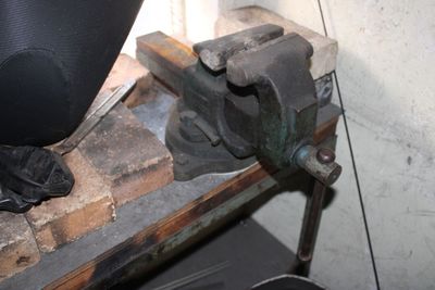a metal clamp that is sitting on top of a piece of wood