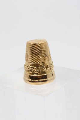 an image of a gold thimble sitting on top of a clear box