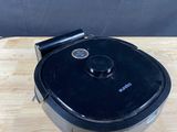 un aspirateur robot noir posé sur une table en bois