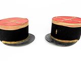 pair of black and red hats with gold trims on a white background
