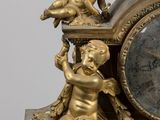 a gold clock with a statue of a boy and a girl on it