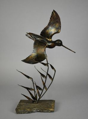 sculpture en bronze représentant un oiseau volant au-dessus des roseaux, posée sur un socle en bois