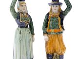 pair of ceramic figurines of a man and a woman with cups on their heads