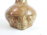a brown vase with a face on it on a white surface