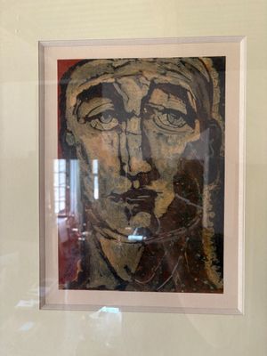 painting of a man ' s face in a white frame on a wall