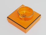 une boîte orange surmontée d'un anneau, posée sur une surface blanche