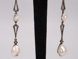 a pair of pearl and silver earrings on a black stand