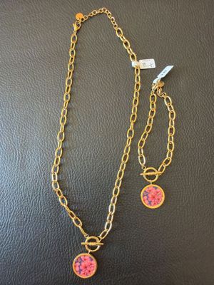 un collier et un bracelet ornés d'une fleur rose sur une chaîne en or