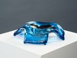 une sculpture en verre représentant un crabe posée sur un socle blanc