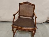 une image représentant une chaise en bois dont l'assise est recouverte d'un tissu marron