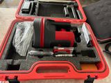 une mallette rouge contenant des outils, posée par terre