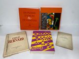 Plusieurs livres sont posés sur une surface blanche ; ils ont des couvertures orange.