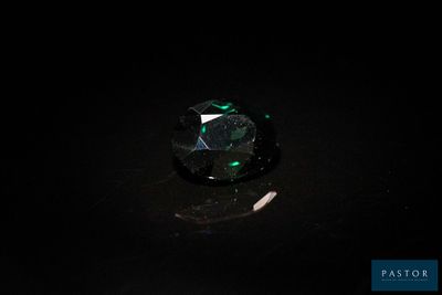 gros plan d'un diamant vert sur une surface noire