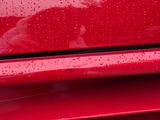 a close up of a red car with rain on it