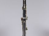 a black and gold clarinet sitting on top of a clear stand
