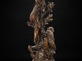 a bronze statue of a woman holding a bird on a pedestal