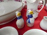a red table cloth with white dishes and a vase with a duck on it