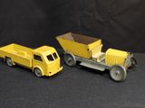 two yellow toy trucks sitting next to each other on a black surface