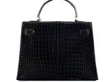 a black crocodile skin handbag on a white background