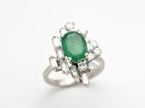 gros plan d'une bague avec une pierre verte entourée de diamants
