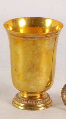 a gold cup sitting next to a coin on a table