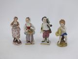 quatre figurines d'enfants vêtus de costumes traditionnels et tenant des paniers