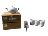 une théière blanche et quatre tasses posées sur une boîte