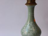 a green vase on a gold stand with a white background