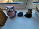 une petite figurine de chouette posée sur le rebord d'une fenêtre, à côté d'une pile de livres
