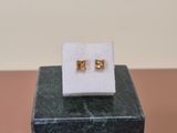pair of gold stud earrings on a marble block on top of a marble block